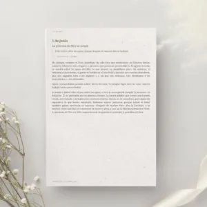 Vista recta de una página impresa del devocional de Charles Spurgeon de junio en fondo gris claro con flores blancas secas. Recursos cristianos.
