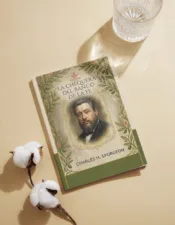 Devocional "La Chequera del Banco de la Fe" de Charles Spurgeon, impreso con estética botánica de Ecos del Edén, junto a ramas de algodón y un vaso de agua sobre una superficie beige.