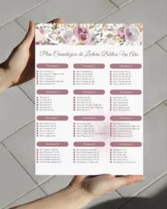 Manos sosteniendo hoja impresa de plan cronológico de lectura bíblica en PDF con flores violeta sobre piso de losetas.