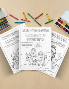 Hojas de colorear en PDF sobre el viaje a Belén con versículos bíblicos, rodeadas de crayones y acuarelas sobre una mesa de madera.